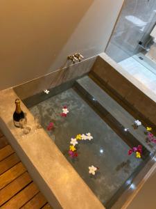 a pool of water with flowers and a bottle of wine at Tropicália chalés boutique in Pipa