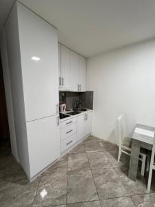 a white kitchen with a table and a white refrigerator at Aurora apartment in Sombor