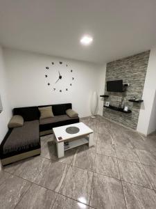 a living room with a couch and a clock on the wall at Aurora apartment in Sombor
