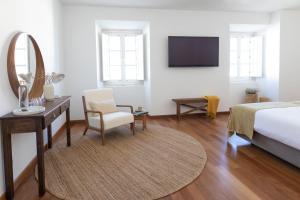 a bedroom with a bed and a desk and a mirror at Casa do Gadanha in Estremoz