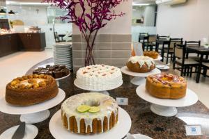 a table topped with cakes and other desserts on plates at Centromar Hotel in Balneário Camboriú