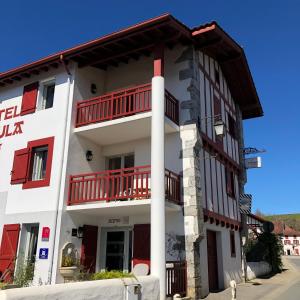 - un grand bâtiment blanc avec des balcons rouges dans l'établissement Hôtel Ursula, à Cambo-les-Bains