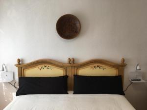 a bed with a wooden headboard and a clock on the wall at LA PLAYA in Retamar