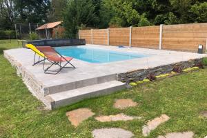 una silla amarilla sentada junto a una piscina en Modern family house with a furnished terrace swimming pool and parking en Pessac