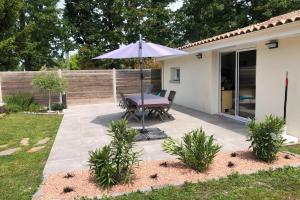 een patio met een tafel en een parasol bij Modern family house with a furnished terrace swimming pool and parking in Pessac