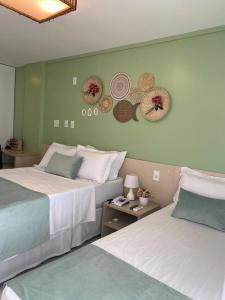 two beds in a hotel room with hats on the wall at Gran Lençóis Flat Residence Mandacaru 311 - 611 in Barreirinhas