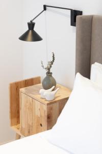 a bedside table with a vase and a lamp at Casa do Gadanha in Estremoz