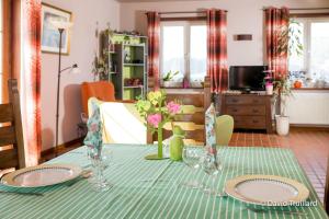 uma mesa com pratos e copos numa toalha de mesa verde em B&B Au fil des saisons sur la Wiels em Fauvillers
