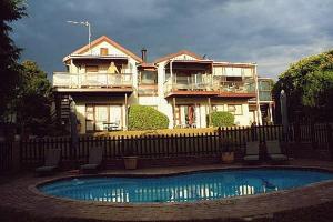 a house behind a fence with a pool in front of it at Swallows Nest Plett in Plettenberg Bay