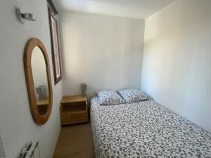 ein kleines Schlafzimmer mit einem Bett und einem Spiegel in der Unterkunft Appartement Puy-Saint-Vincent in Puy-Saint-Vincent