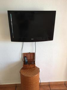 a flat screen tv hanging on a wall with a wicker table at LA PLAYA in Retamar