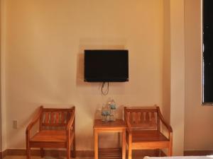Habitación con 2 sillas y TV en la pared. en Dag, en Nha Trang