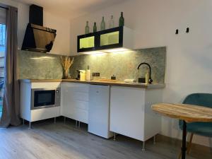 a kitchen with white cabinets and a sink and a table at Les Jardins Secrets - Gare & Centre by Apparts Spa Dijon in Dijon +36 photos