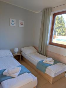 2 łóżka pojedyncze w pokoju z oknem w obiekcie Morskie Opowieści w mieście Mikoszewo