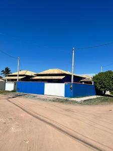 um edifício azul e branco ao lado de uma estrada de terra batida em Casa com piscina para temporada - Unamar, Cabo Frio - RJ em Cabo Frio