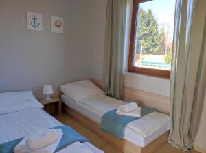 2 łóżka pojedyncze w pokoju z oknem w obiekcie Morskie Opowieści w mieście Mikoszewo