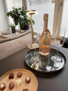 Luxury Omuntu-Design-Apartment Deluxe في ميونخ: طاولة مع كأسين وزجاجة من النبيذ والشوكولاته