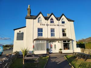 een wit gebouw met een bord dat het Queens hotel leest bij The Queens Hotel Harlech in Harlech