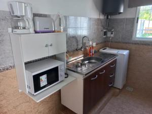 una pequeña cocina con fregadero y microondas en Casa quinta duplex Tortuguitas en Tortuguitas