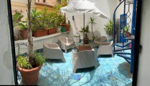 パレルモにあるCharming loft con Terrazze al Teatro Massimoの白い椅子と鉢植えの植物が備わるパティオ