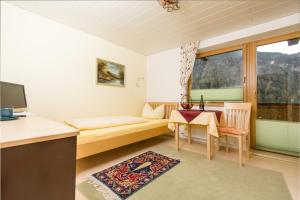 een woonkamer met een tafel, een bank en een raam bij Gästehaus Helga in Scharnitz