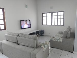 a living room with a couch and a flat screen tv at Linda Casa, 3 quartos, acomoda 10 pessoas, há 1,5 km da praia da Enseada in Guarujá