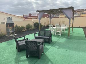 un patio con sillas, mesa y cenador en Villa Kareva, en Caleta de Fuste