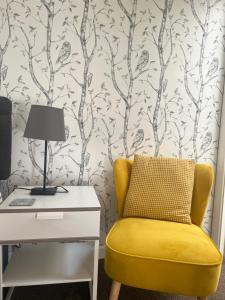 a yellow chair next to a desk with a lamp at Anchor Inn in Taunton