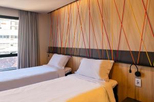 阿雷格里港的住宿－ibis Styles Porto Alegre Moinhos de Vento，酒店客房设有两张床和窗户。