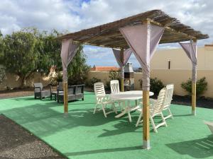 a patio with a table and chairs on a green lawn at Villa Kareva in Caleta De Fuste