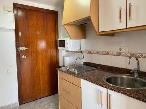 eine kleine Küche mit einem Waschbecken und einer Holztür in der Unterkunft Apartamento 19th floor & sea view in Alicante