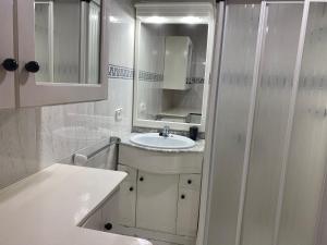 ein weißes Badezimmer mit Waschbecken und Spiegel in der Unterkunft Apartamento 19th floor & sea view in Alicante + 7 Fotos