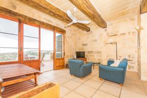 a living room with two chairs and a ceiling fan at Farmhouse Cala2 in Qala