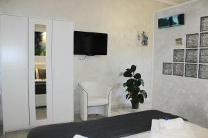 een slaapkamer met een bed en een stoel en een tv aan de muur bij Cozy House in Tivoli
