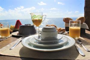 una mesa con un plato de comida y vasos de zumo de naranja en Bali Praia, en Arraial d'Ajuda