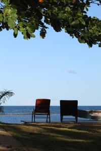dos sillas sentadas en la playa cerca del agua en Bali Praia, en Arraial d'Ajuda