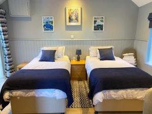a bedroom with two beds with blue and white sheets at Gracehill Lodge - Guest Accommodation in Stranocum