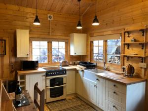 uma cozinha com armários brancos e um forno com placa de fogão em The Chalet @ Giltar Grove Country House em Tenby