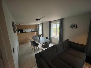 un salon avec un canapé et une table avec des chaises dans l'établissement vakantiehuis nieuwendamme, à Nieuport