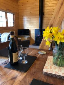 The Chalet @ Giltar Grove Country House في تينبي: زجاجة من النبيذ وأكواب على طاولة خشبية