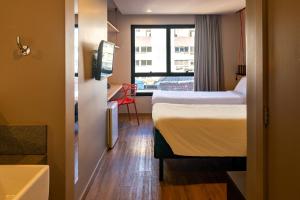 ein Hotelzimmer mit einem Bett und einem Fenster in der Unterkunft ibis Styles Porto Alegre Moinhos de Vento in Porto Alegre