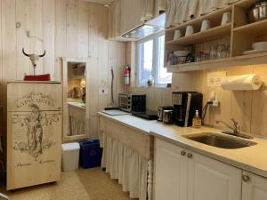 a kitchen with a sink, refrigerator, and cabinets at Appartement champêtre in Saguenay