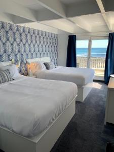 two beds in a hotel room with a view of the ocean at Grand View Hotel in York Beach