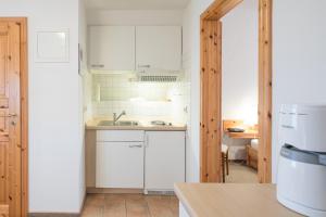 a kitchen with white cabinets and a sink at Direkt am Deich - Ferienwohnung Amrum im Gästehaus Am Badedeich in Dagebüll