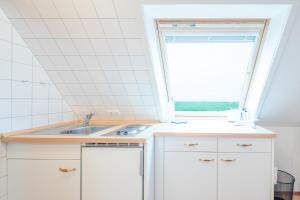 a kitchen with a sink and a window at Direkt am Deich - Ferienwohnung Oland im Gästehaus Am Badedeich in Dagebüll