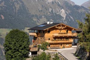 duży drewniany dom z balkonem w górach w obiekcie Bergsuite Pfaffenebner w mieście Matrei in Osttirol