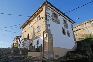 un edificio blanco y marrón con una valla negra en AL SON DE LAS OLAS, en Lastres