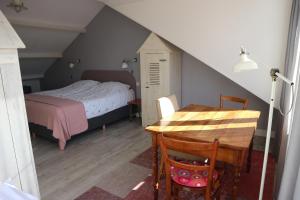 a bedroom with a bed, table and chairs at B&B - Pension Het Oude Dorp in Katwijk