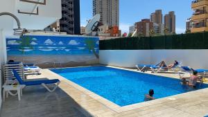 a swimming pool with people sitting in chairs in a city at MY SUNNY PAYMA BEACH Apartment in Benidorm