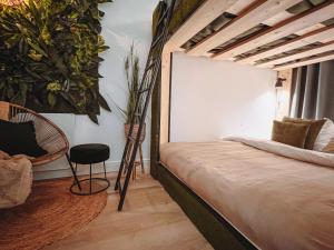 ein Schlafzimmer mit einem Bett, einem Stuhl und Pflanzen in der Unterkunft Abbey Green Lodge in Breda